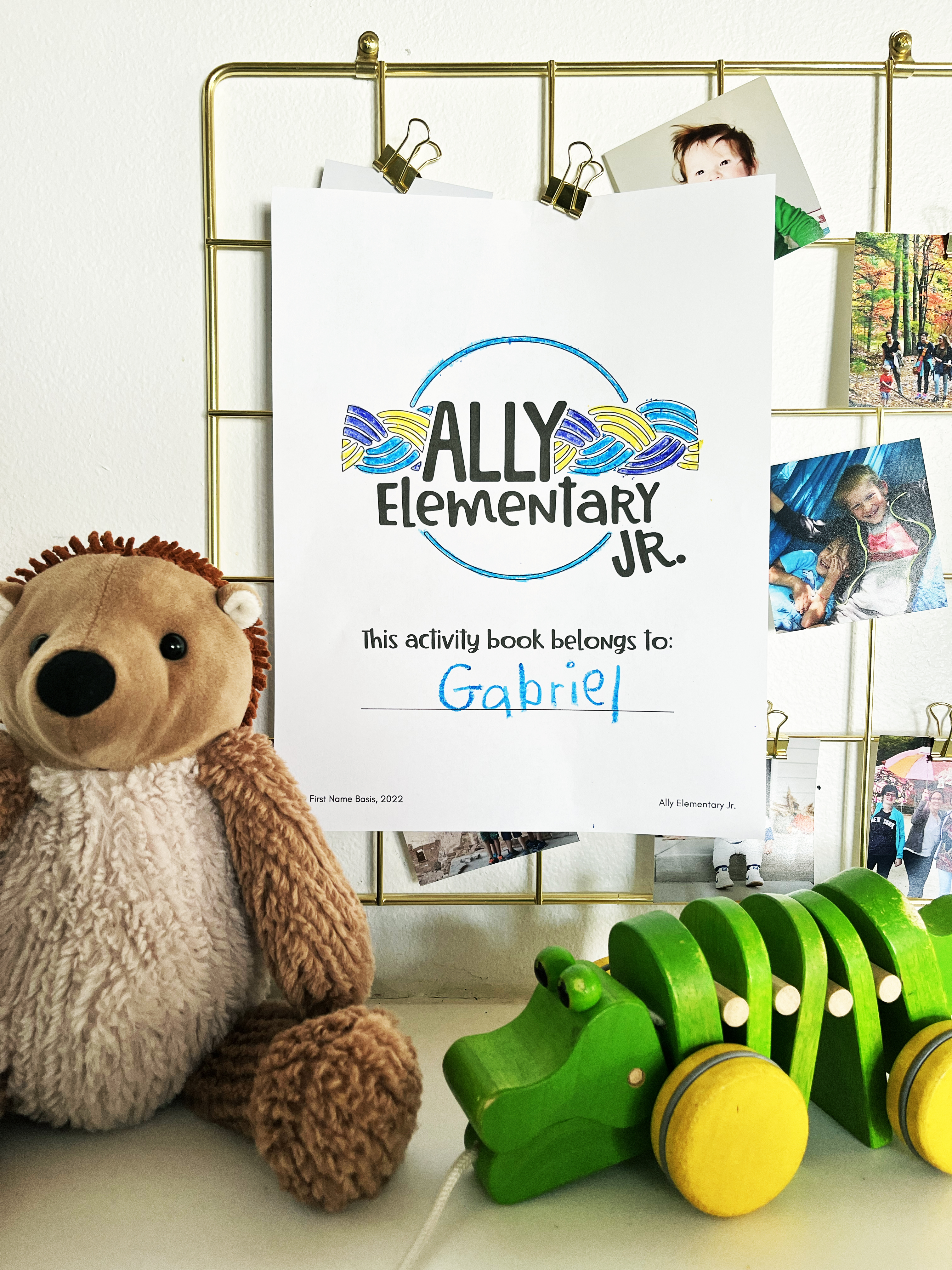 This photo shows the cover of the Ally Elementary Jr. workbook, surrounded by toys and family photos.